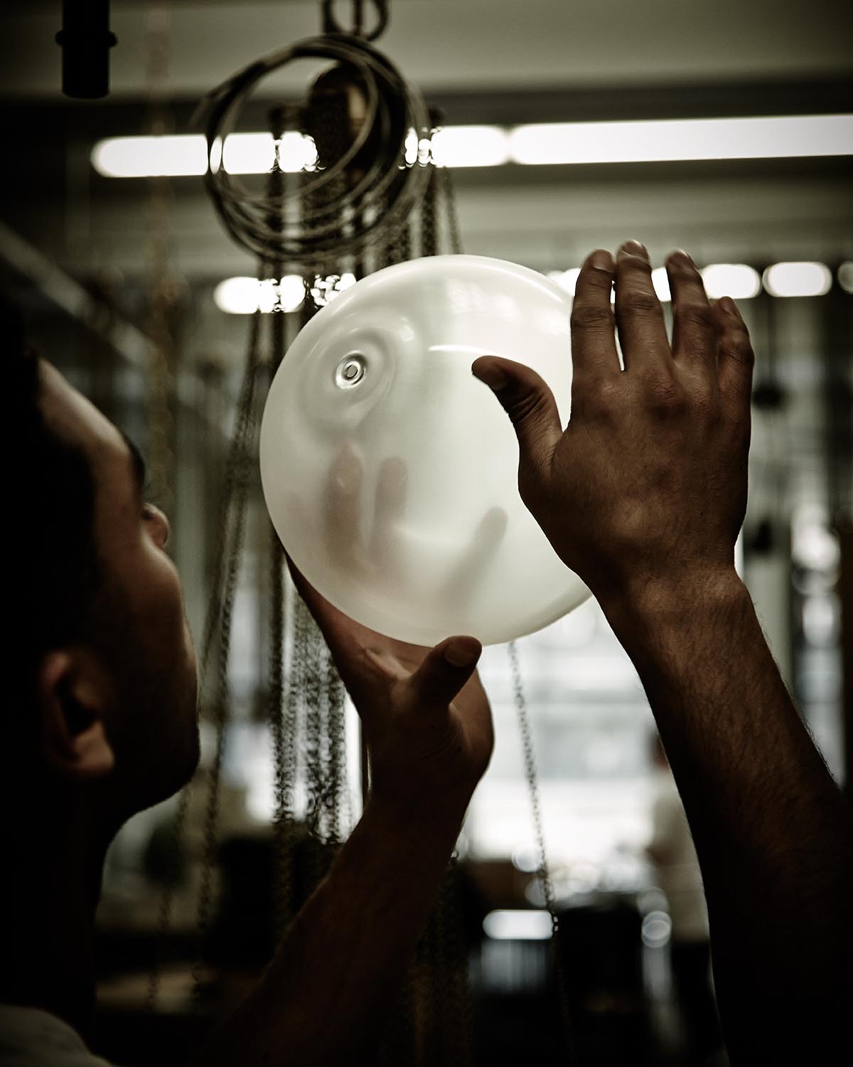 Man inspecting a translucent, inflated balloon-like object in a dimly lit industrial setting