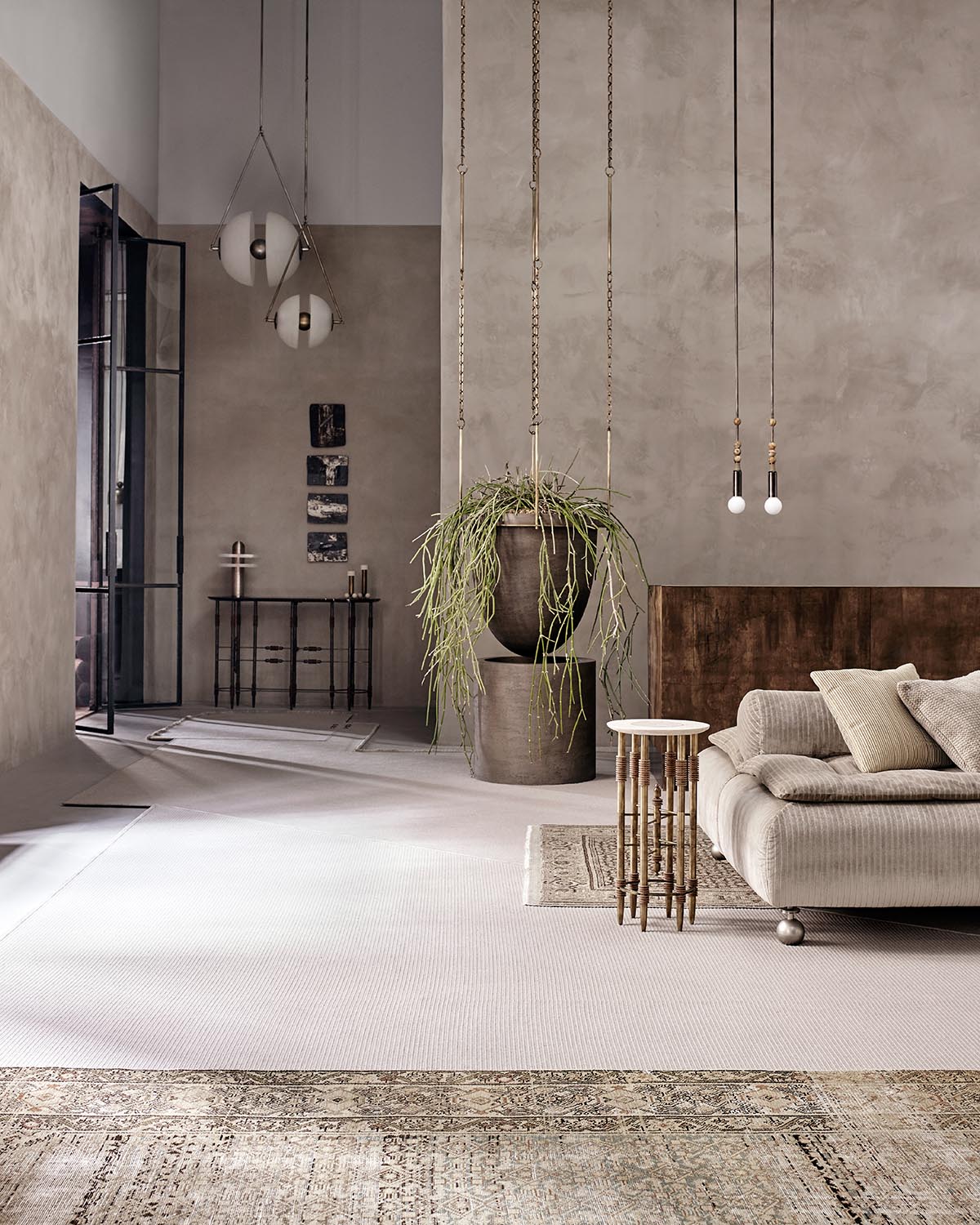 Minimalist living room with textured beige sofa, hanging planter, wooden side table, and pendant lights against taupe walls