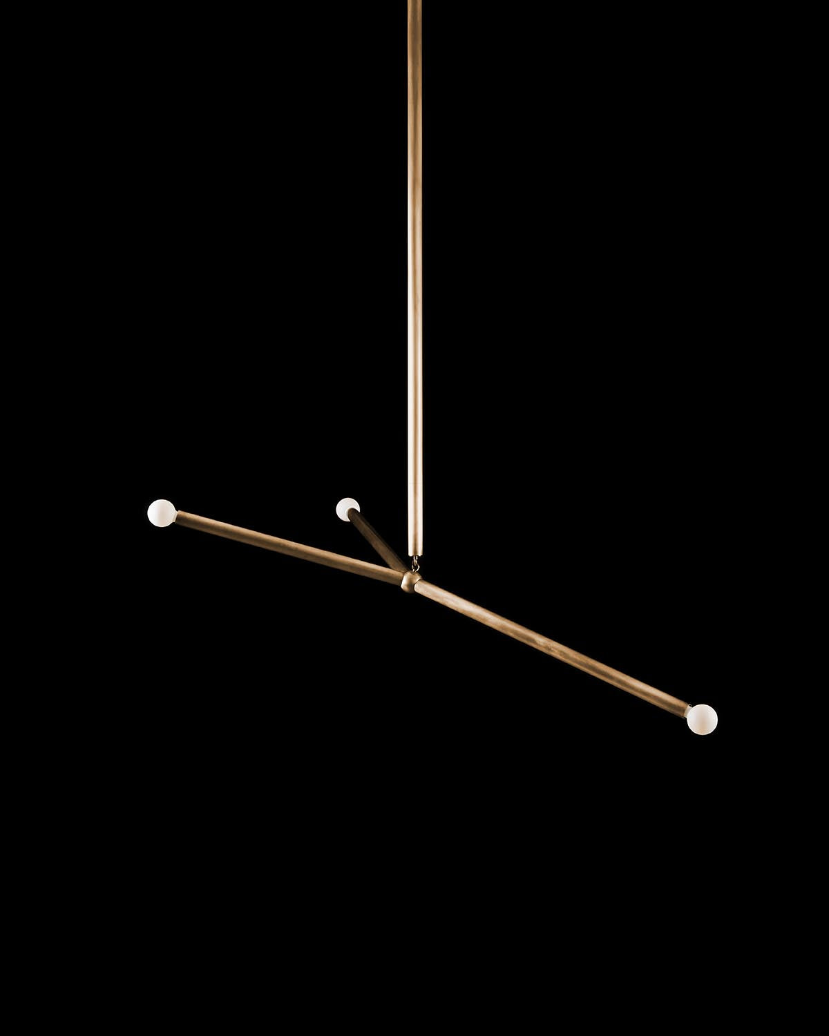 Minimalist pendant light with three horizontal bronze rods and white spherical bulbs against a black background