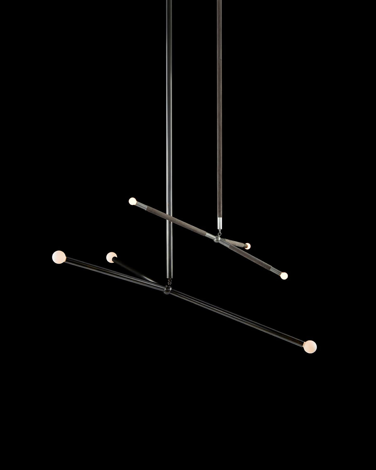 Minimalist hanging light fixture with intersecting black rods and small round white bulbs against black background