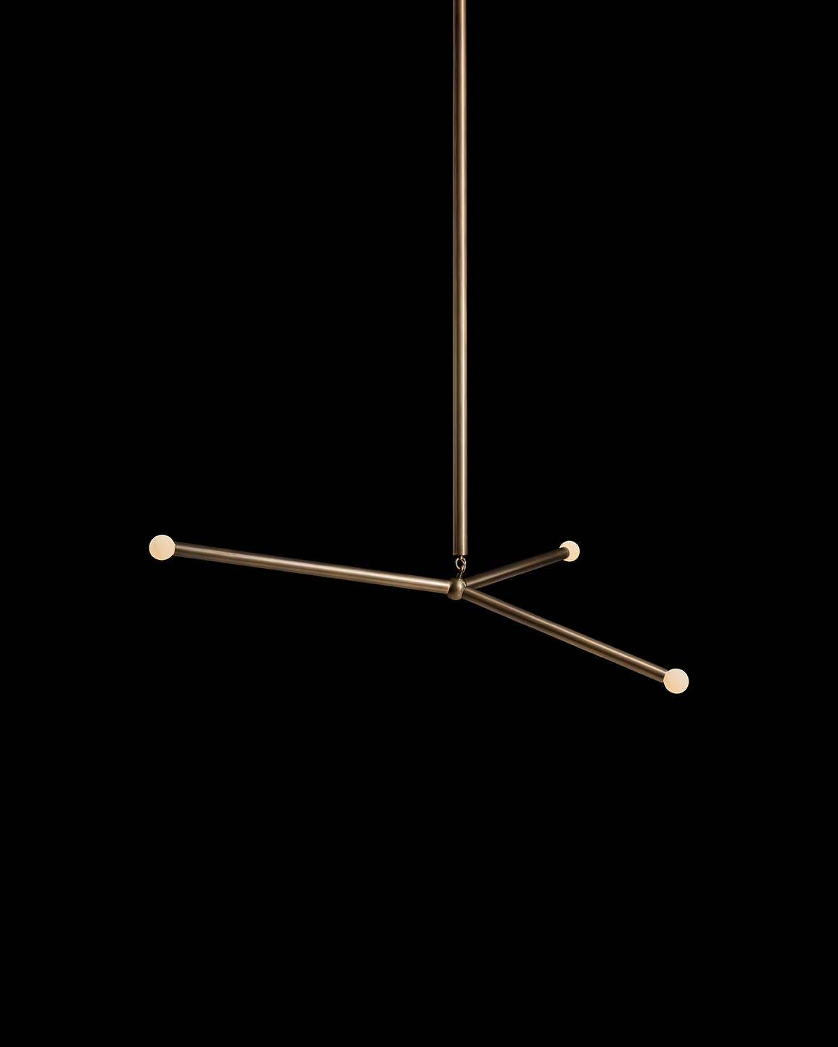 Modern minimalist pendant light with three thin horizontal brass rods and small round bulbs on black background