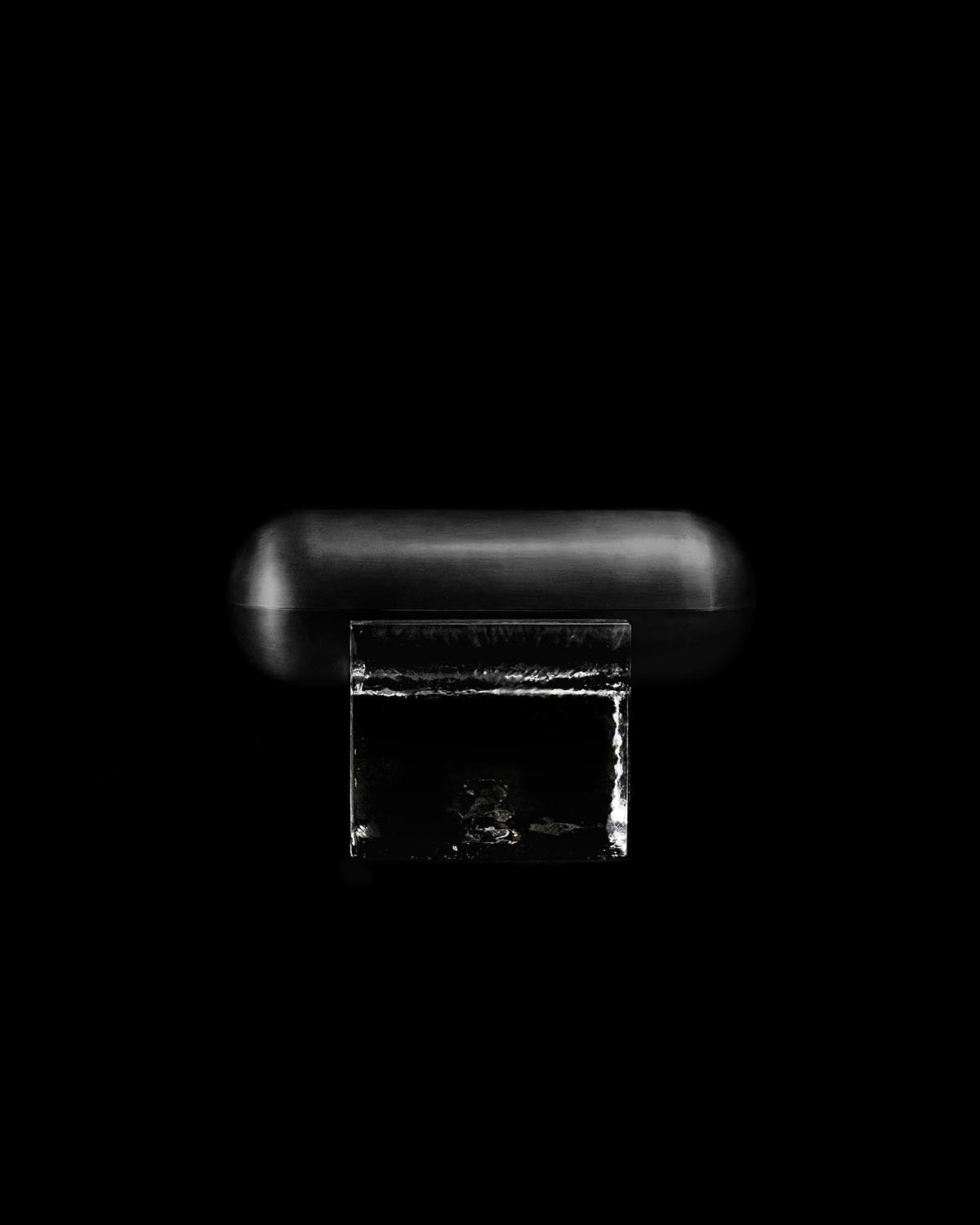 Minimalist black rectangular case with rounded edges displayed on a clear acrylic stand against black background