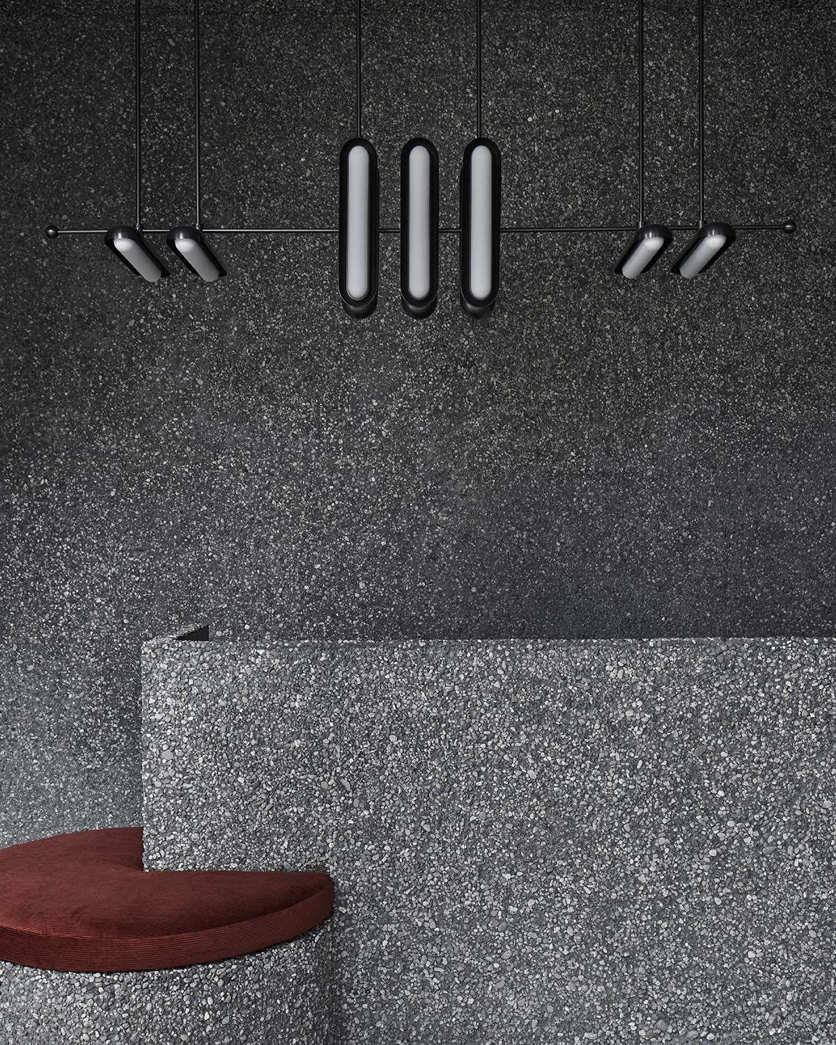 Linear black metal pendant light fixture with elongated oval diffusers against textured dark gray wall