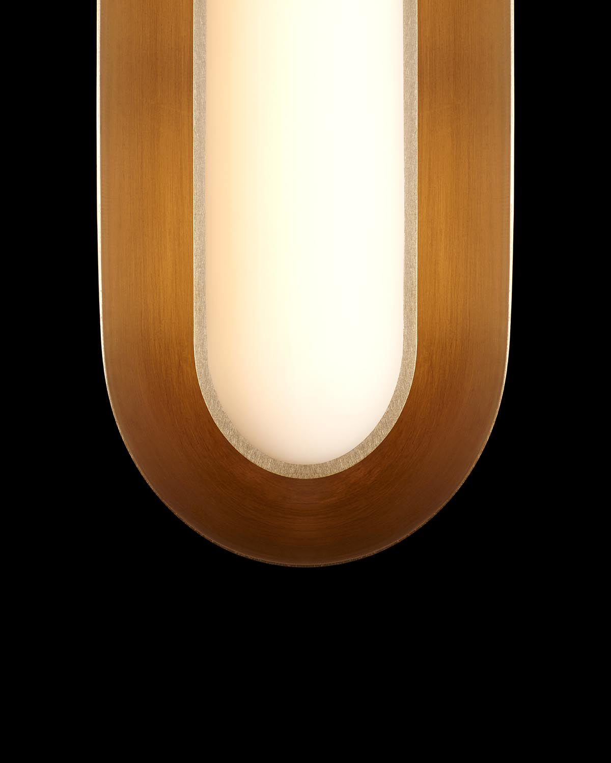 Close-up of elongated oval pendant light with warm brass frame and diffused white glass center against black background