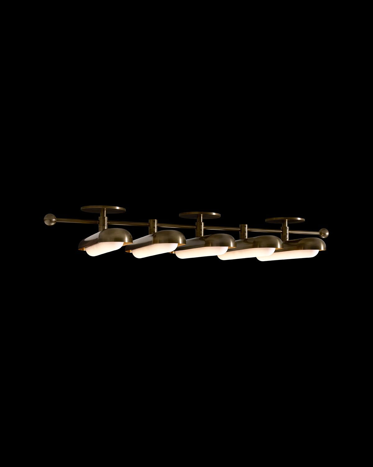 Linear ceiling light fixture with five rounded metallic shades and warm diffused lighting on black background