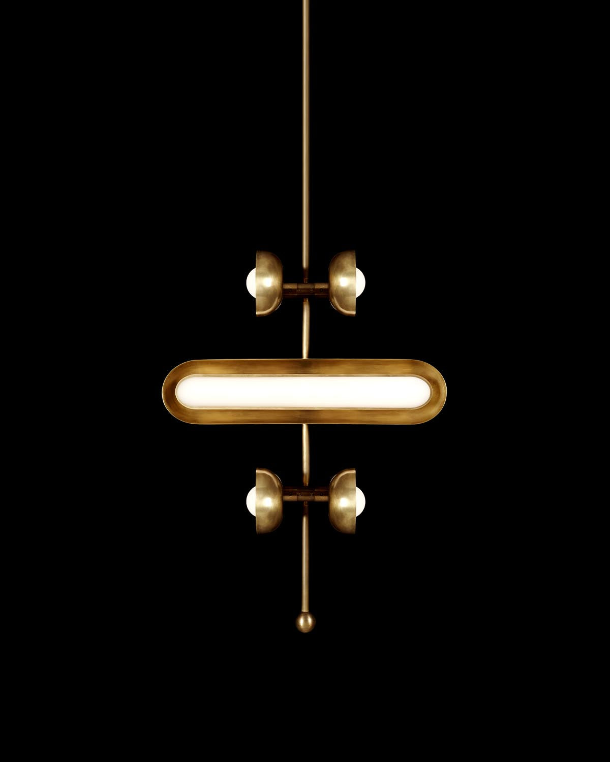 Minimalist brass pendant light with elongated oval diffuser and four round bulbs on vertical rod against black background