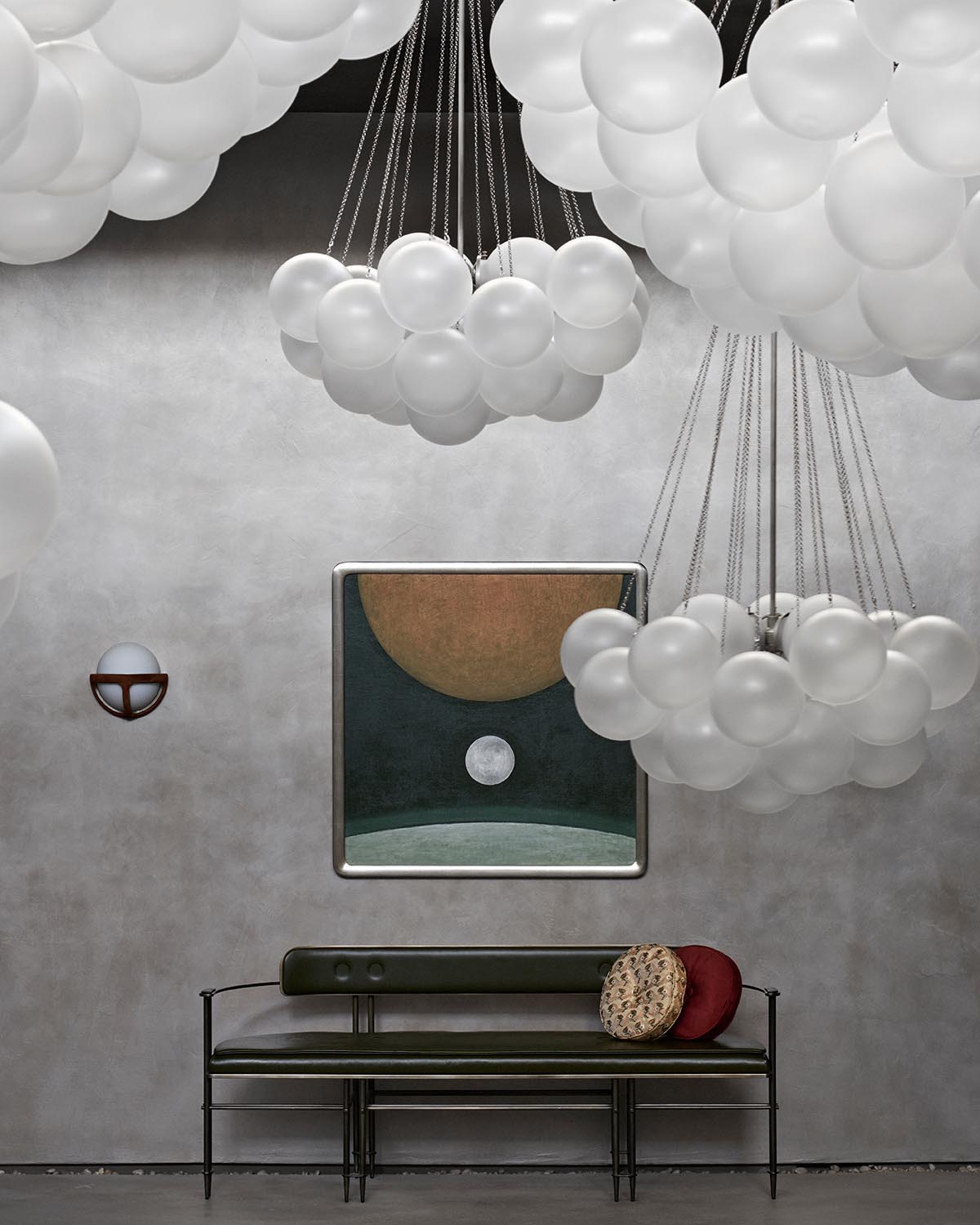 Modern interior with CLOUD pendant lights featuring clustered white spheres above a minimalist bench and abstract wall art on a textured gray wall