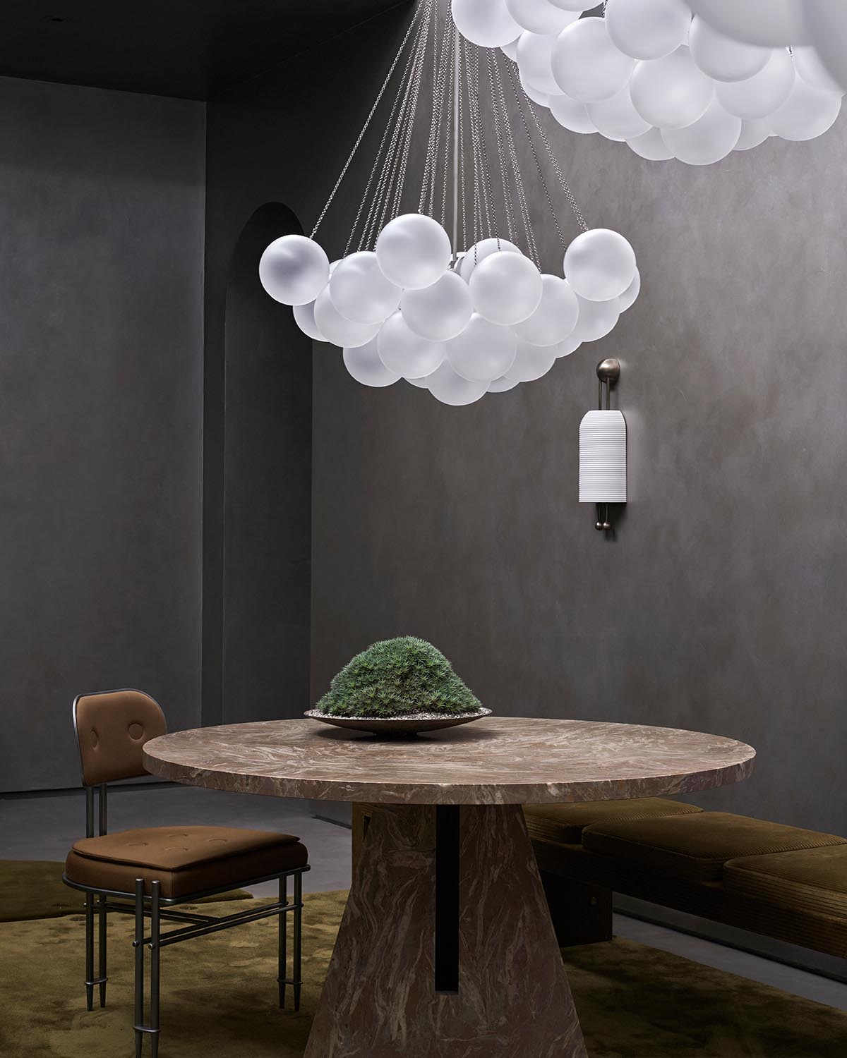 Modern dining area featuring a round stone table and a cloud-like cluster of white globe pendant lights above