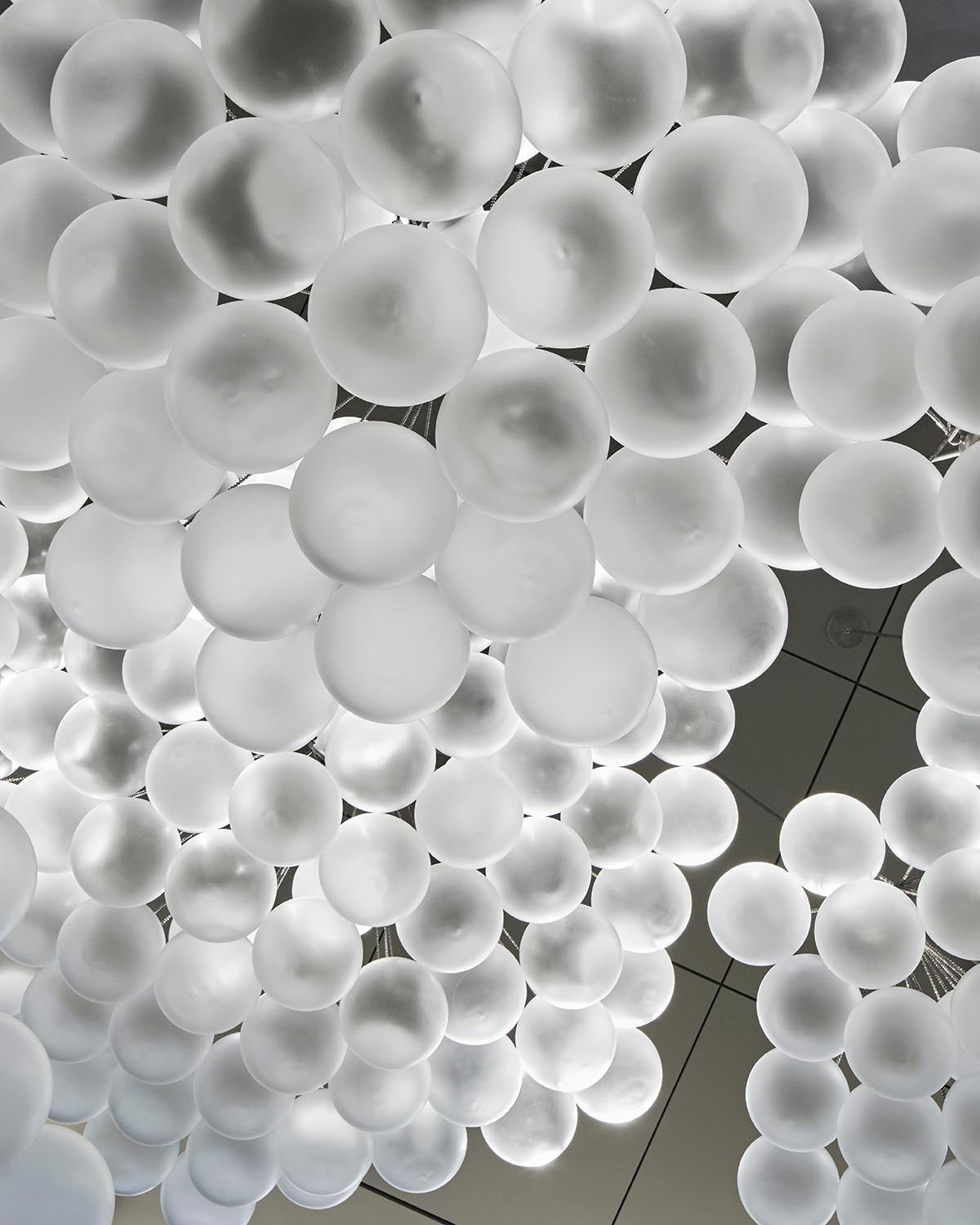 Cluster of frosted glass orb pendant lights grouped closely against a ceiling with grid pattern panels