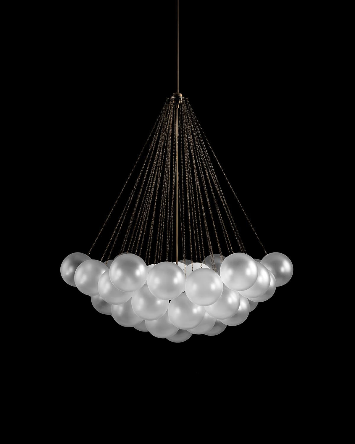 Suspension chandelier with multiple frosted glass globes connected by thin black cables against a dark backdrop