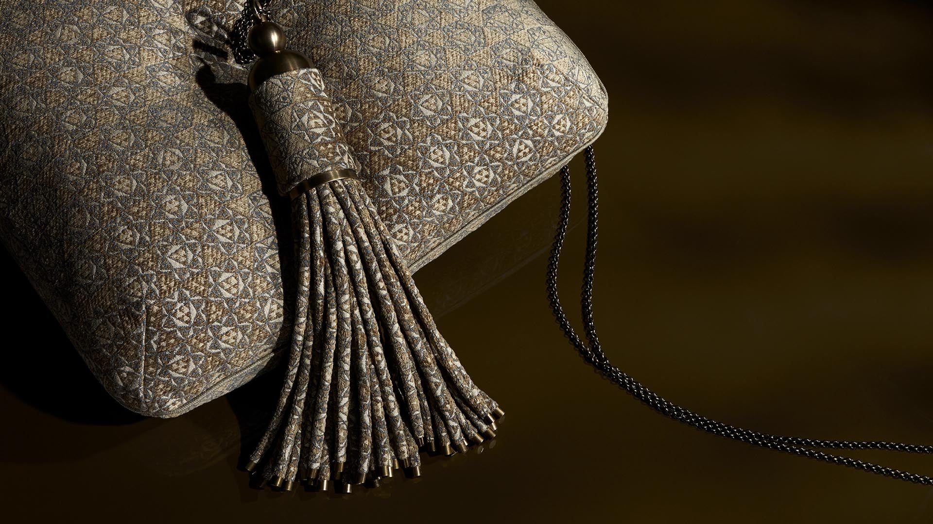 Close-up of a fabric pouch with intricate geometric patterns and a decorative tassel on a dark background
