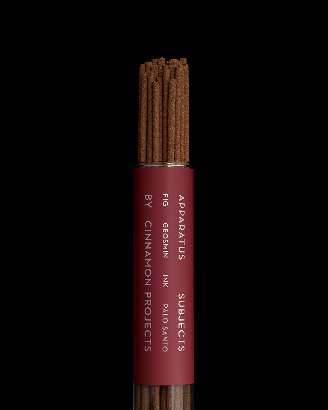 Close-up of cylindrical burgundy container holding brown incense sticks against a black background