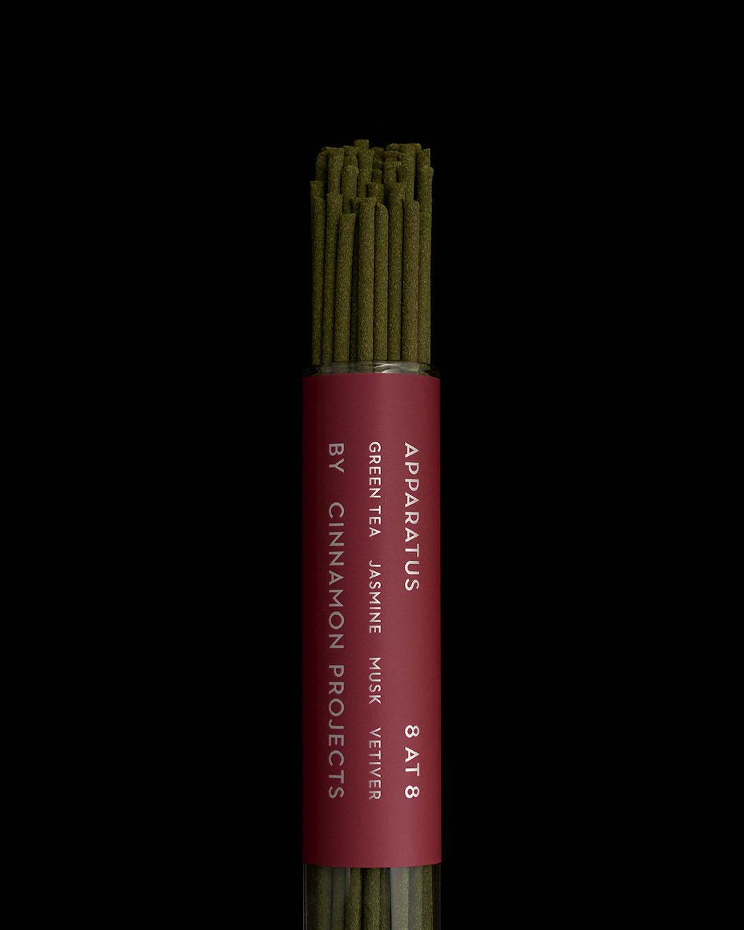 Close-up of green incense sticks bundled inside a cylindrical red container with white vertical text on a black background