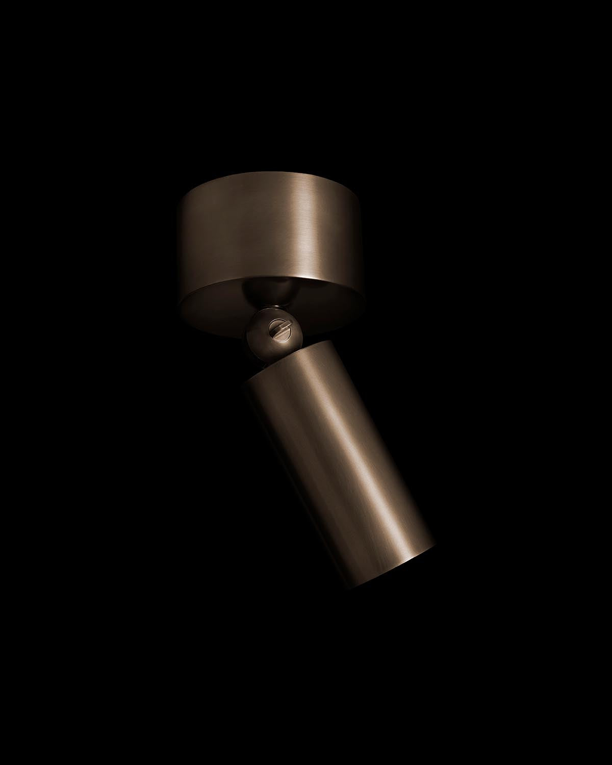 Close-up of a cylindrical downlight fixture in brushed metal finish against a black background