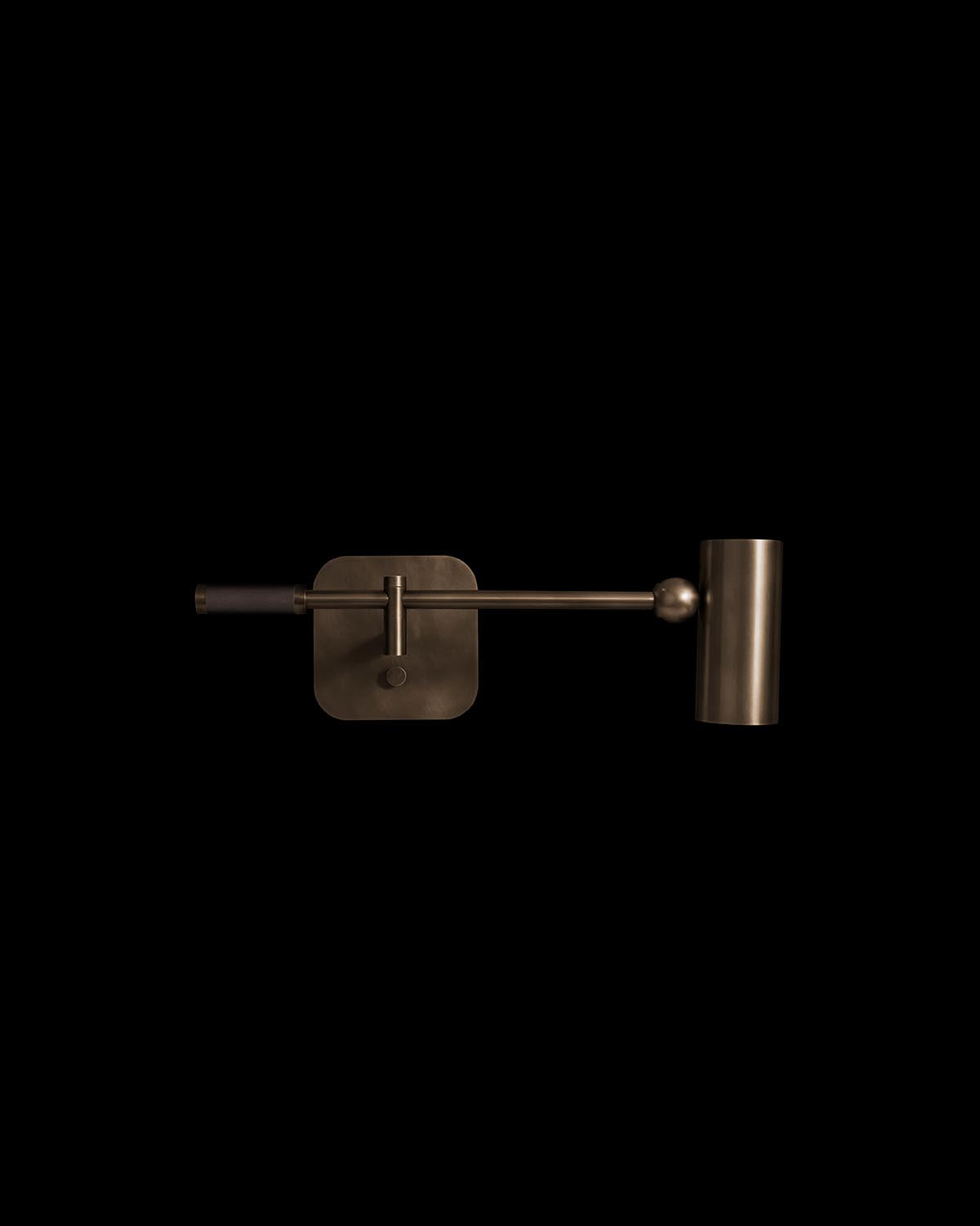 Metallic cylinder reading sconce with an adjustable arm and matte finish mounted on a square backplate against black background