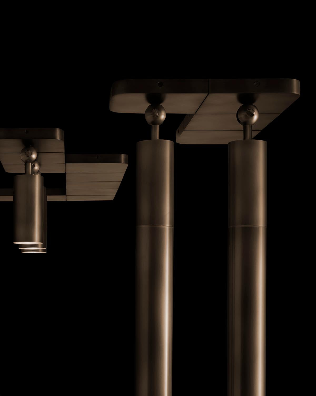 Close-up of sleek cylindrical metal columns with flat rectangular tops against a black background