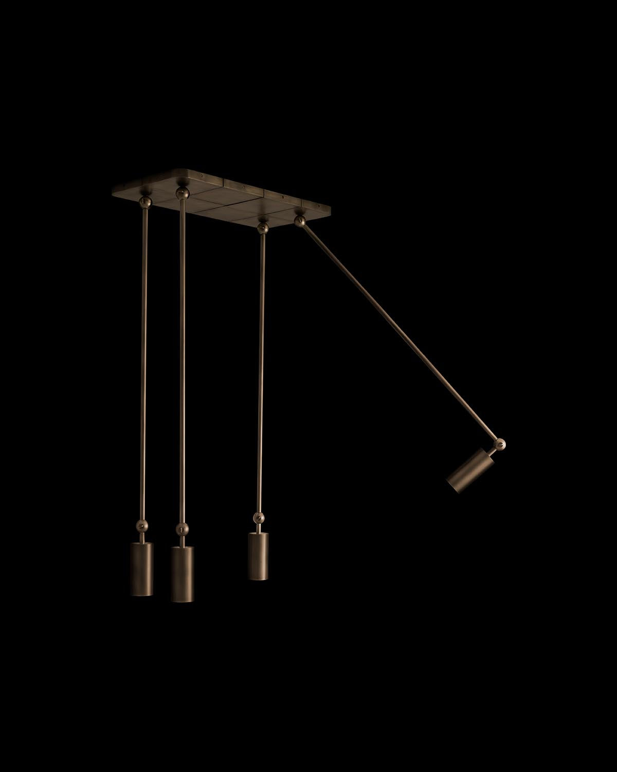 Minimalist ceiling light fixture with three vertical cylindrical pendants and one angled adjustable arm against black background