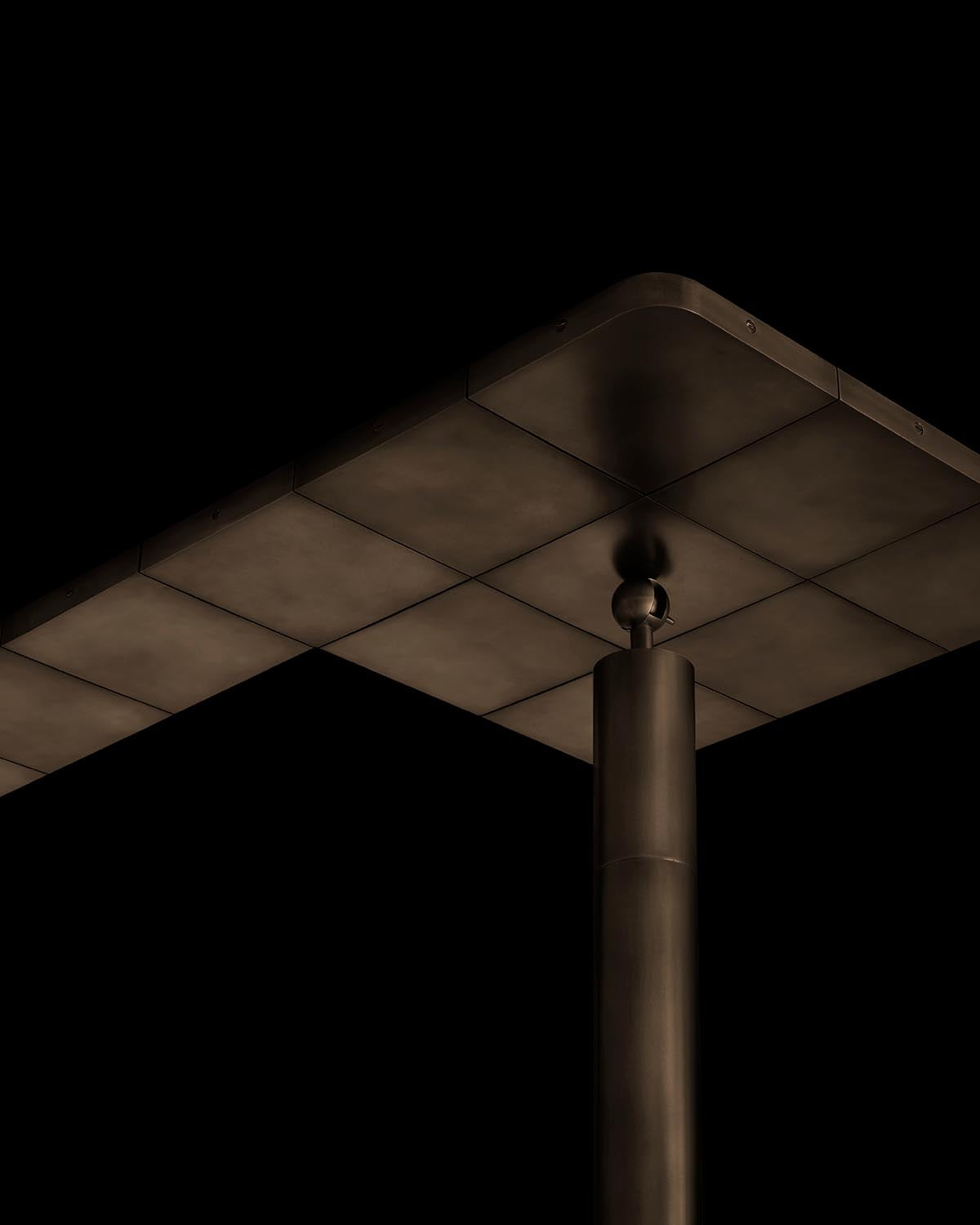 Close-up of matte dark metal cylinder supporting a flat panel with rounded edges against a black background