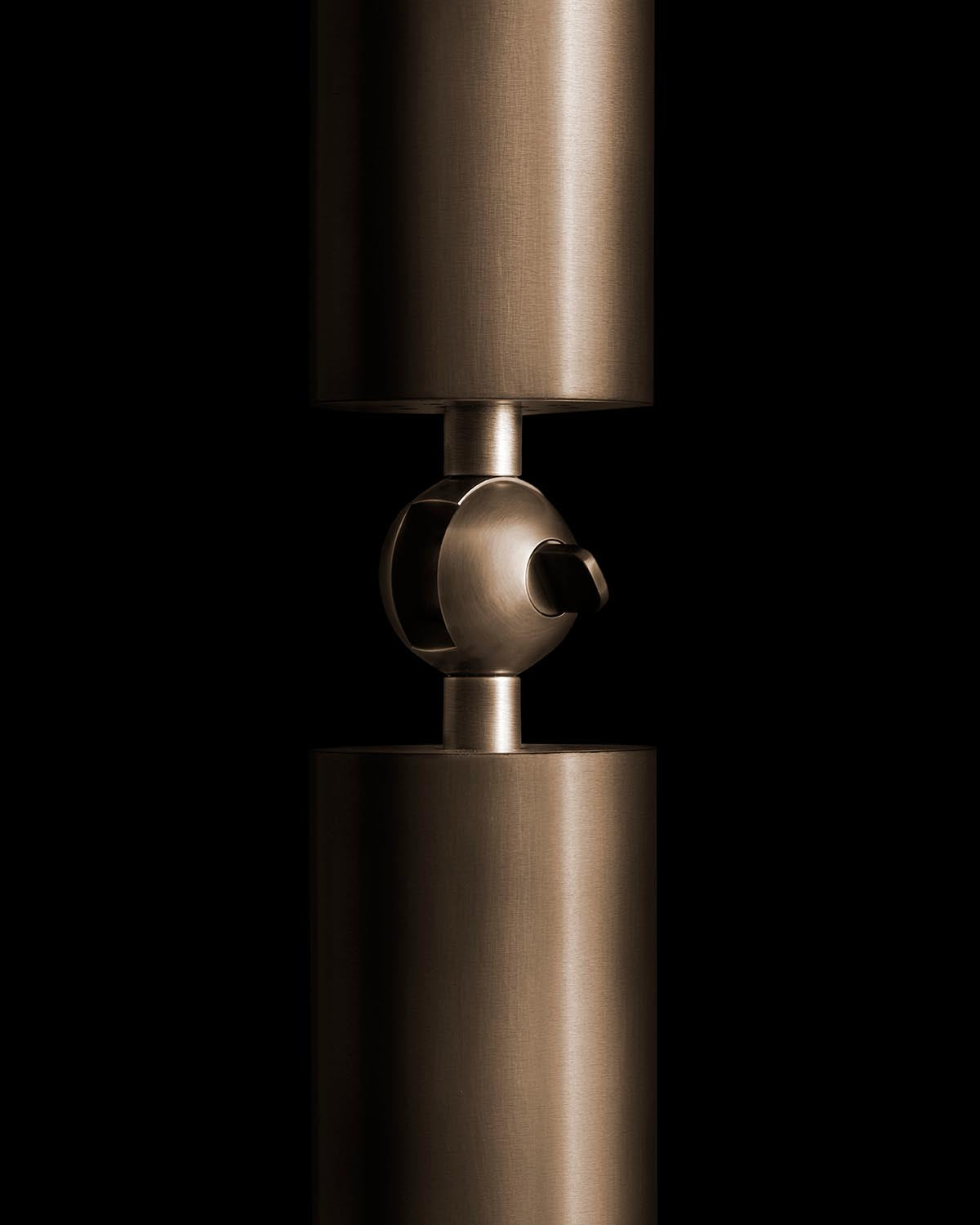 Close-up of a polished bronze cylindrical connector with a spherical joint against a black background