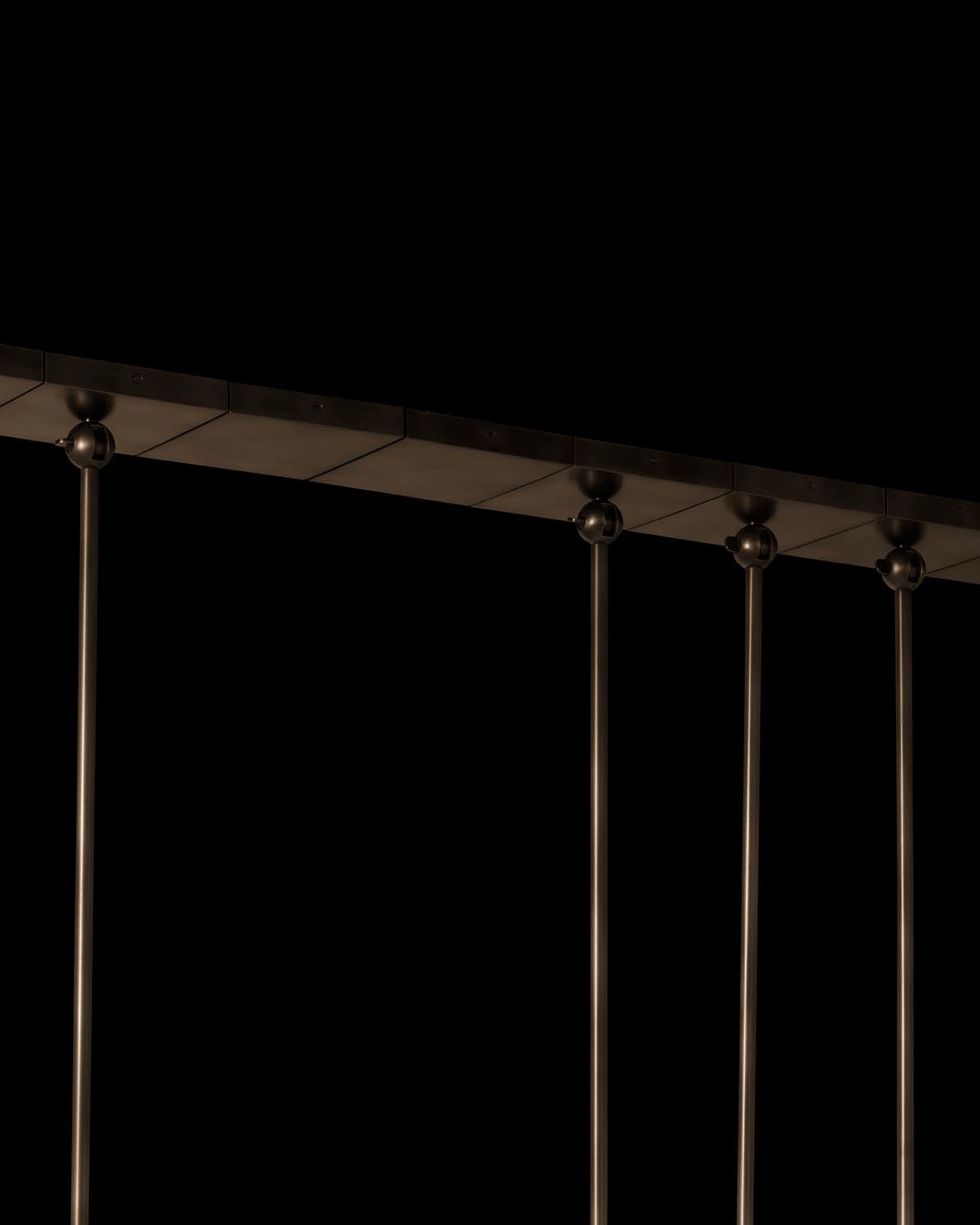 Close-up of a sleek black metal hanging fixture with a row of four suspension rods against a dark background