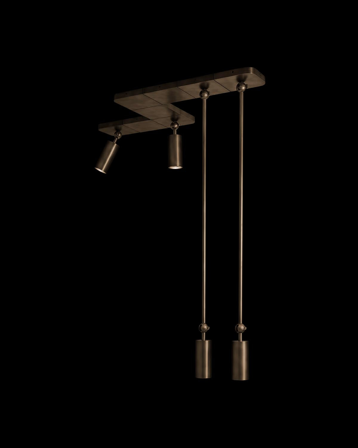 Modern ceiling light fixture with two long pendants and an adjustable spotlight in dark metal finish against black background