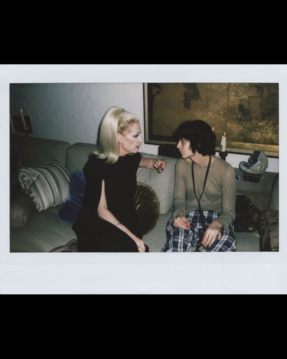 Two people sitting closely on a couch, engaged in a serious conversation in a softly lit room.