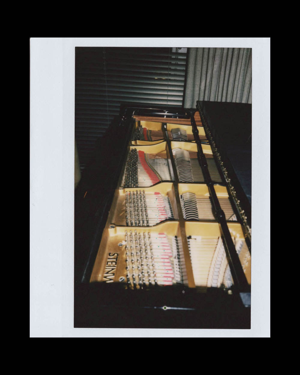 Close-up view of the internal strings and hammers of a grand piano with a partially open lid indoors.