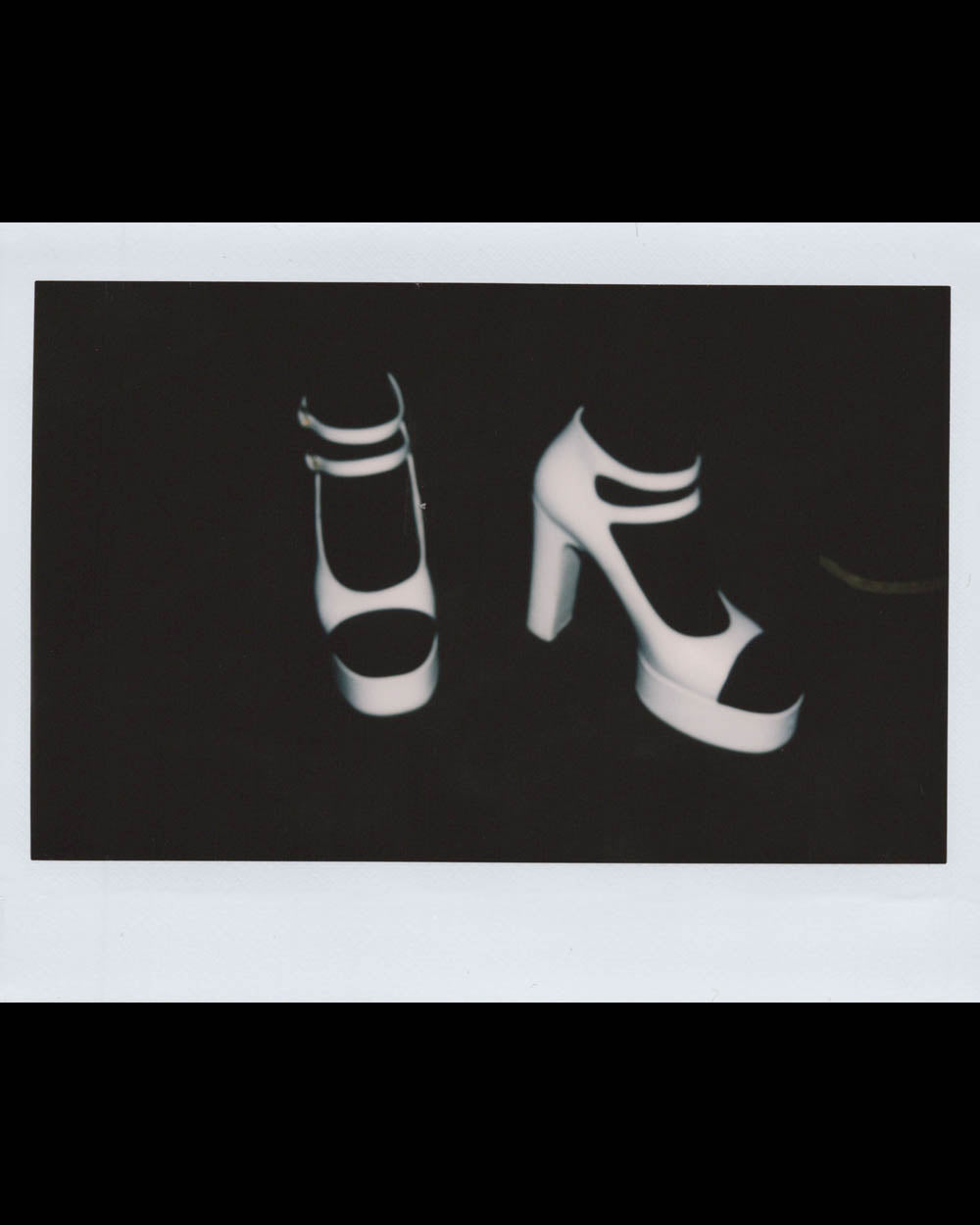 Pair of white platform heels with double ankle straps against a dark background