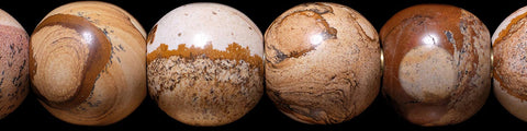 Close-up of polished round natural stone spheres with varied earthy brown and beige patterns against a white background