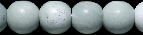 Close-up of smooth round pale green beads with subtle marbling on a black background
