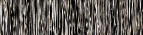 Close-up of densely packed vertical natural fiber strands in varying shades of gray and beige against a dark background