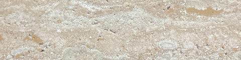 Close-up of a beige travertine stone surface with natural texture and irregular patterns on a neutral background