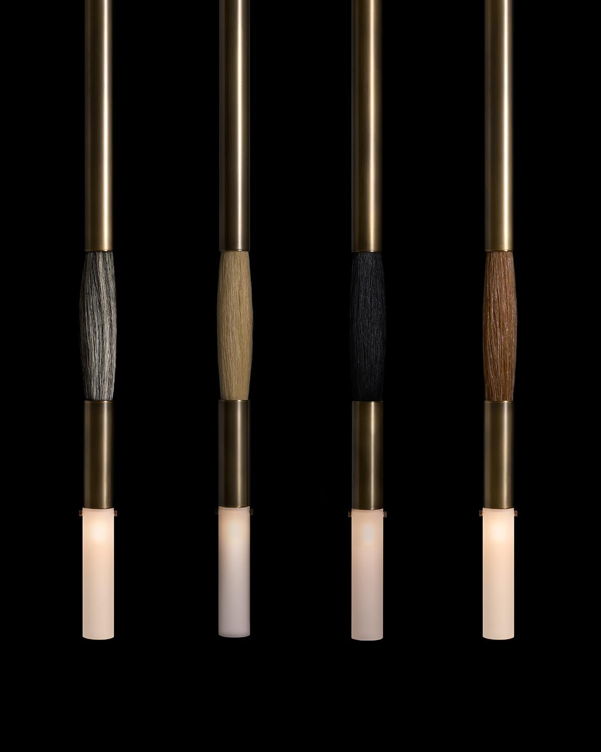 Four vertical pendant lights with brass rods, cylindrical frosted glass shades, and horsehair-wrapped midsections in varied colors