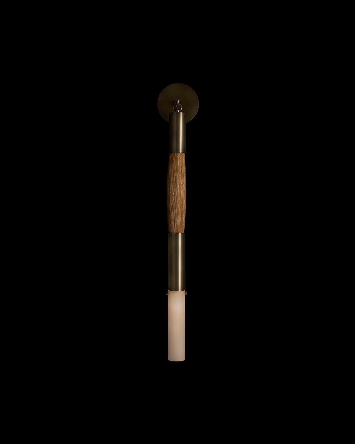 Vertical single sconce with matte brass finish and a textured wooden midsection against a black background