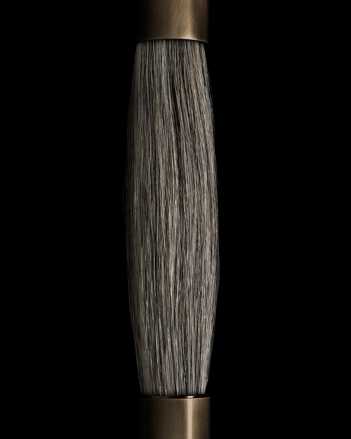 Close-up of textured horsehair strand detail between two brushed metal fixtures on black background