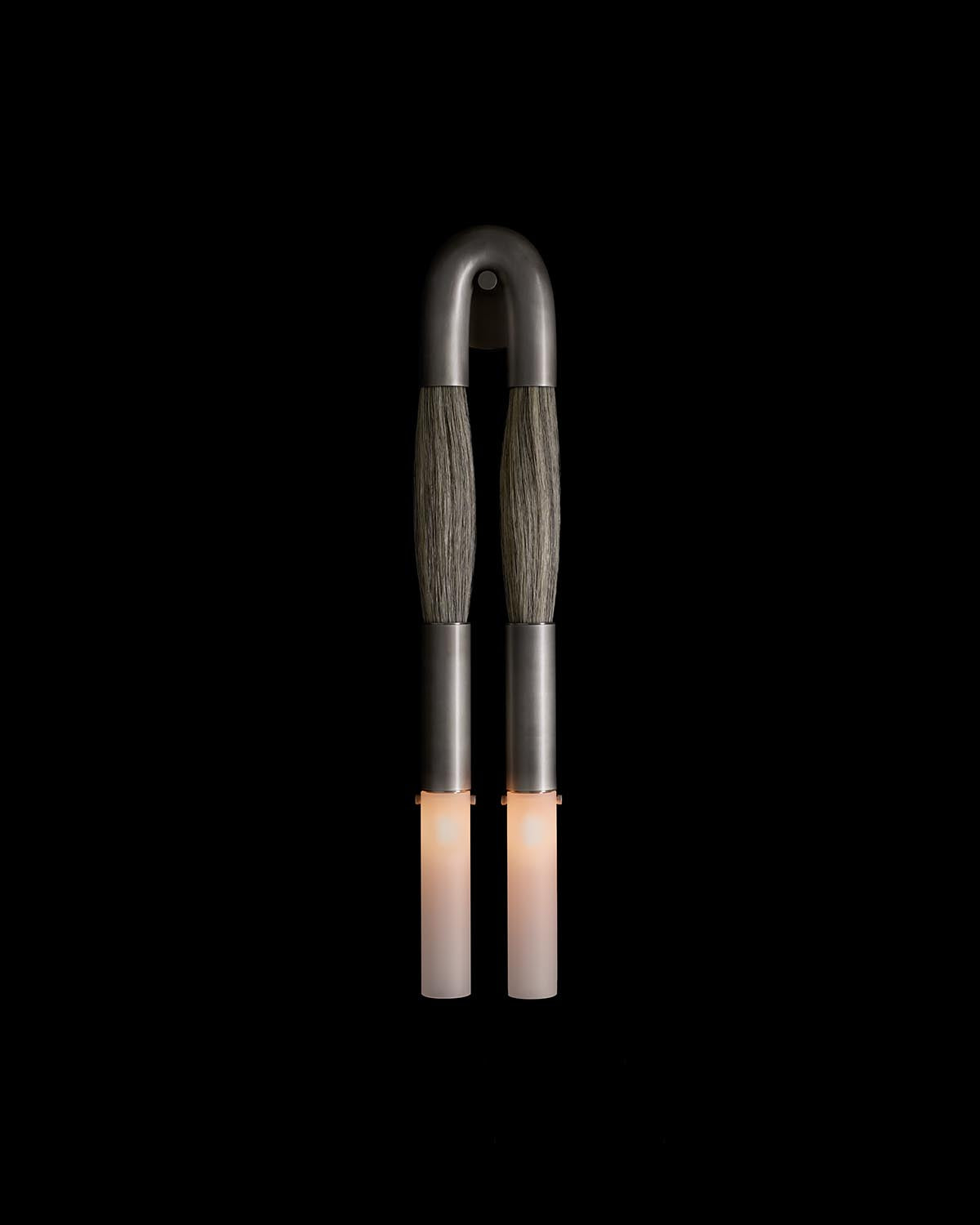 Modern dual wall sconce with curved dark metal frame and elongated cylindrical frosted glass shades emitting soft light