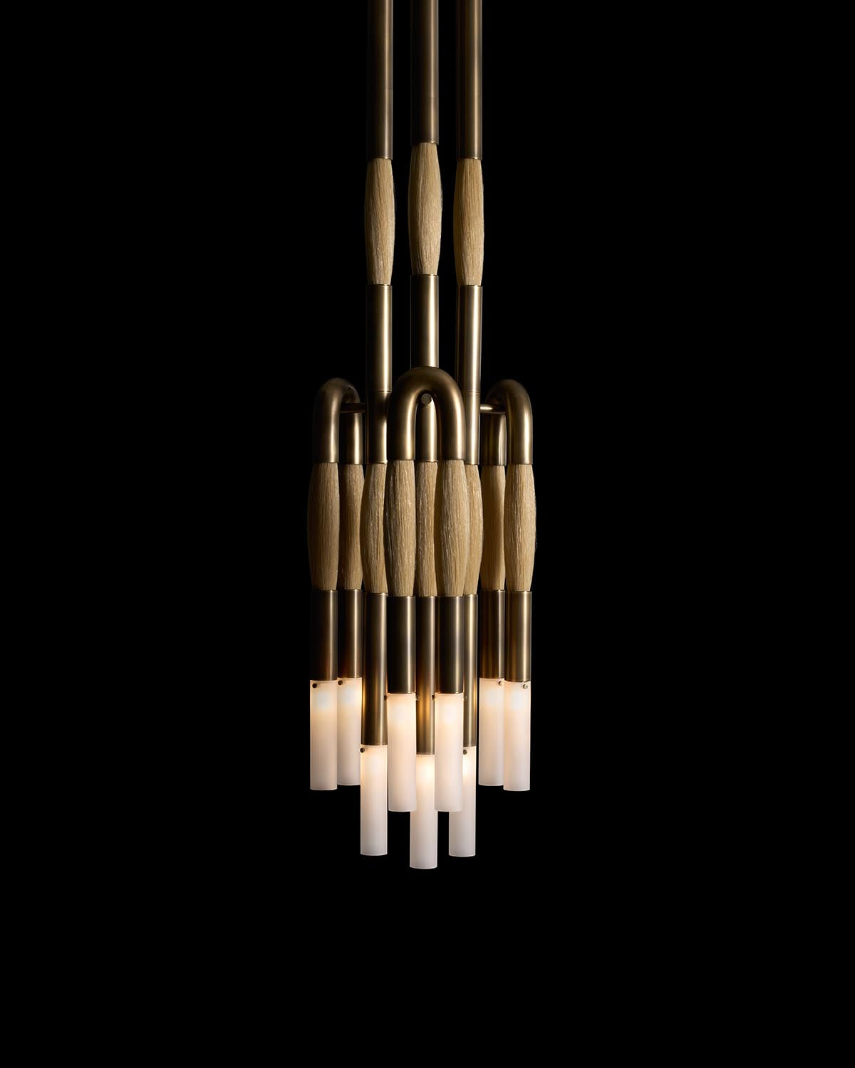 Cluster of nine pendant lights with brass pipes and wooden accents, glowing softly against a black background
