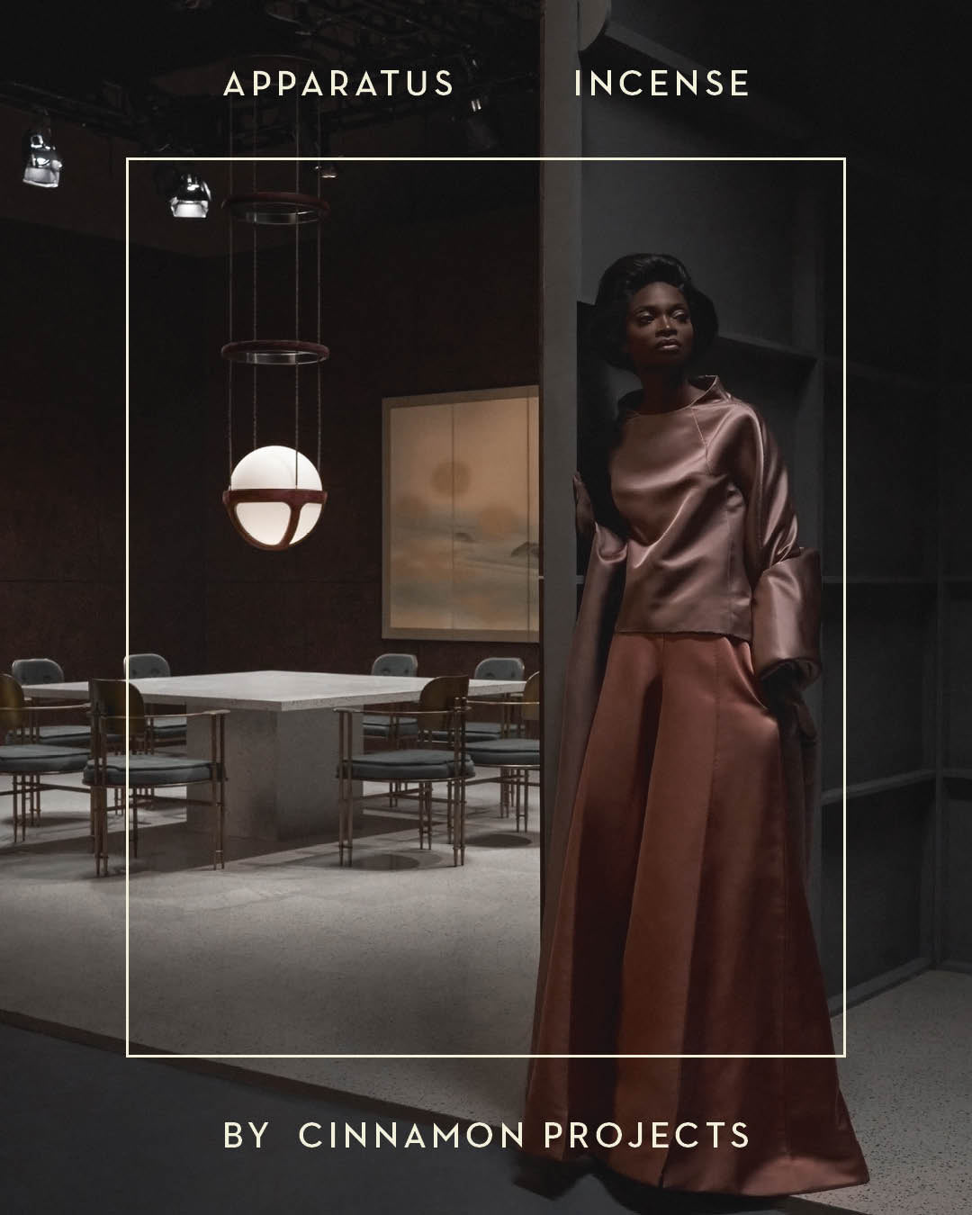 Moody interior scene with modern dining table and chairs lit by pendant light, woman in satin outfit leaning on dark wall
