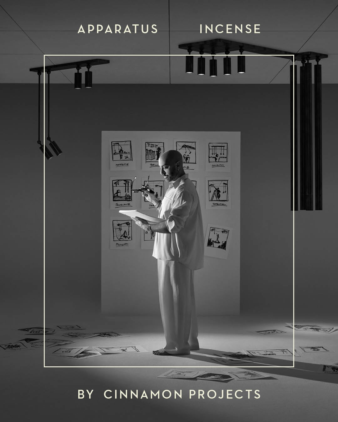 Black and white image of a person sketching on paper pinned to a wall surrounded by scattered drawings on the floor