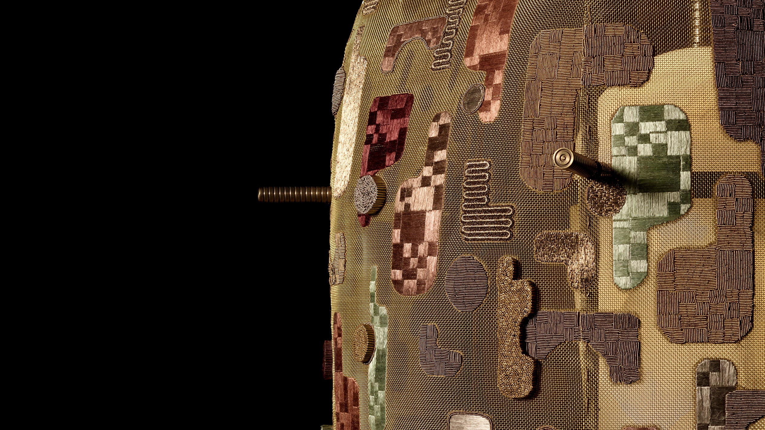 Close-up side view of a textured abstract sculpture with geometric patterns and protruding metallic rods against black background