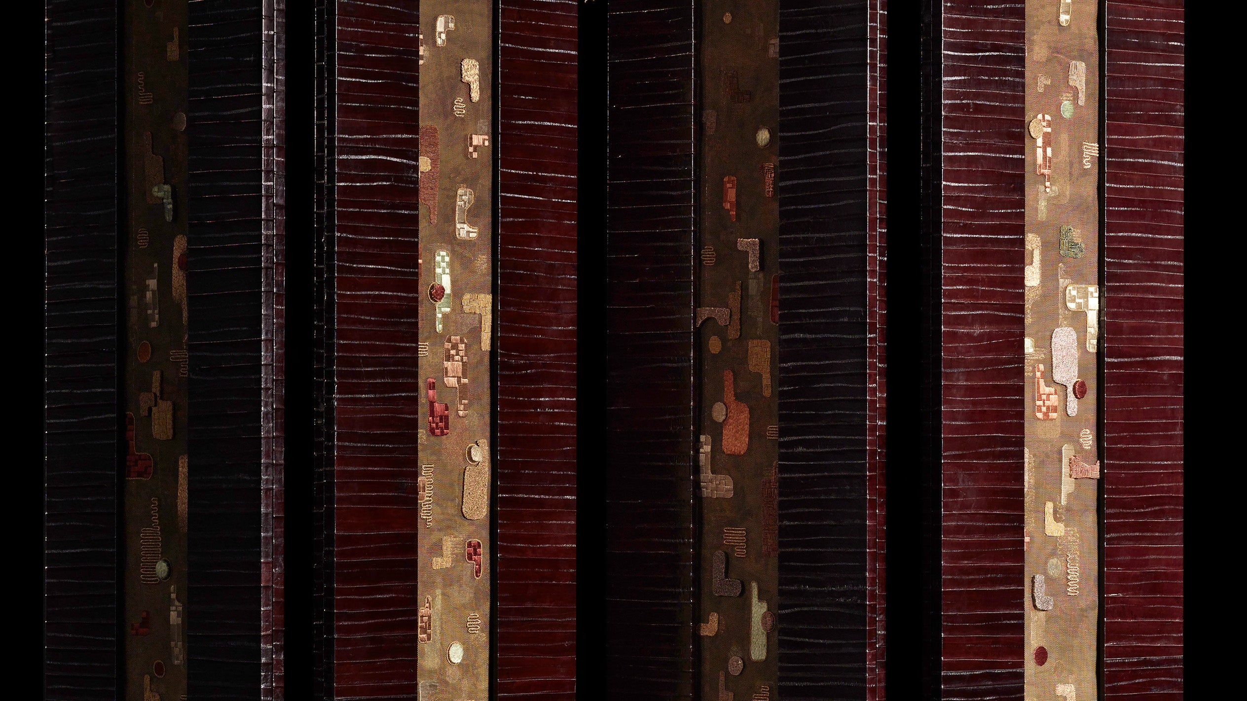 Vertical dark wooden slats with narrow metallic strips featuring abstract patterns against a black background