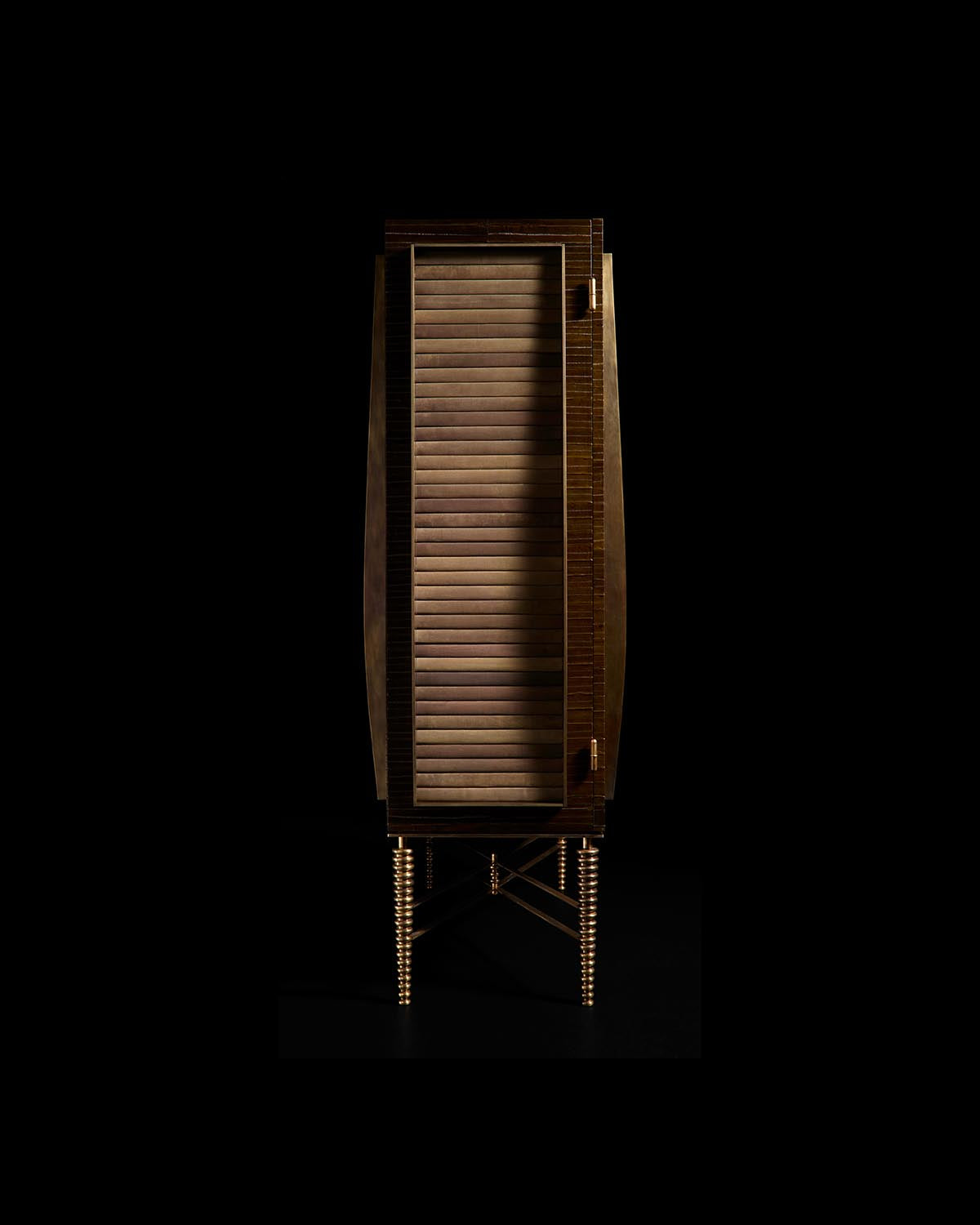 Tall wooden cabinet with horizontal slatted door and slender spiral legs in a dark studio setting