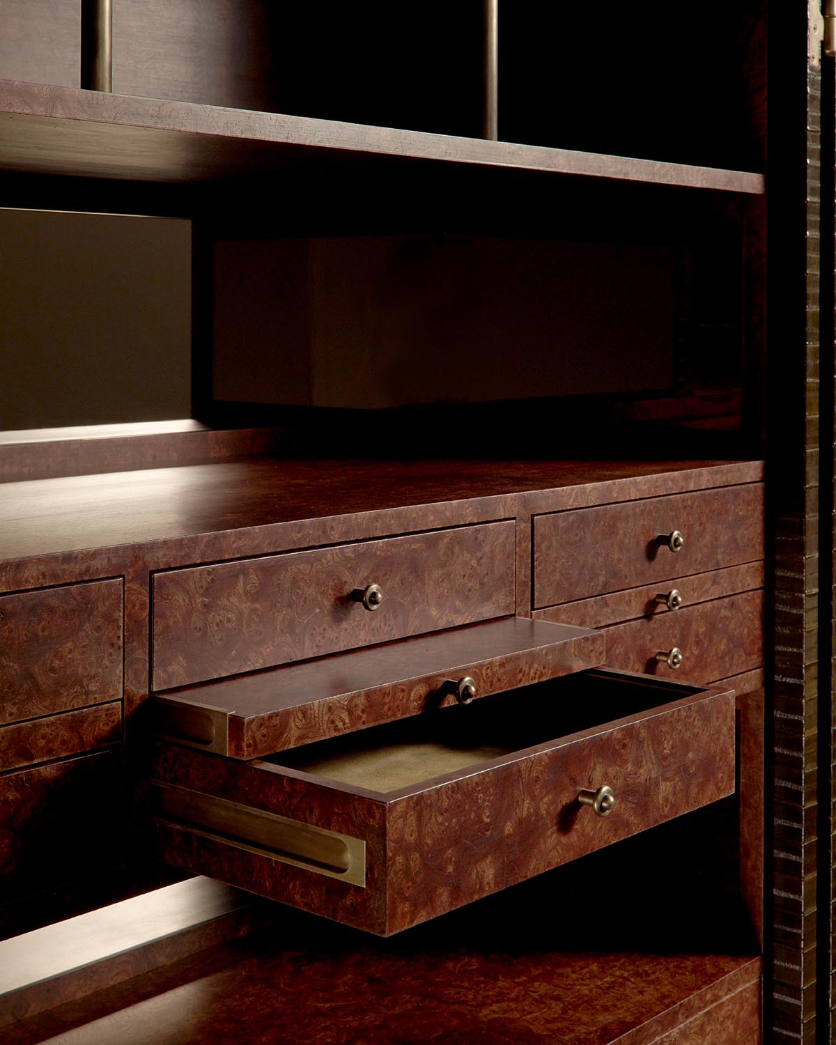 Close-up of a dark wood cabinet with multiple drawers, one drawer partially open showing its smooth interior surface.