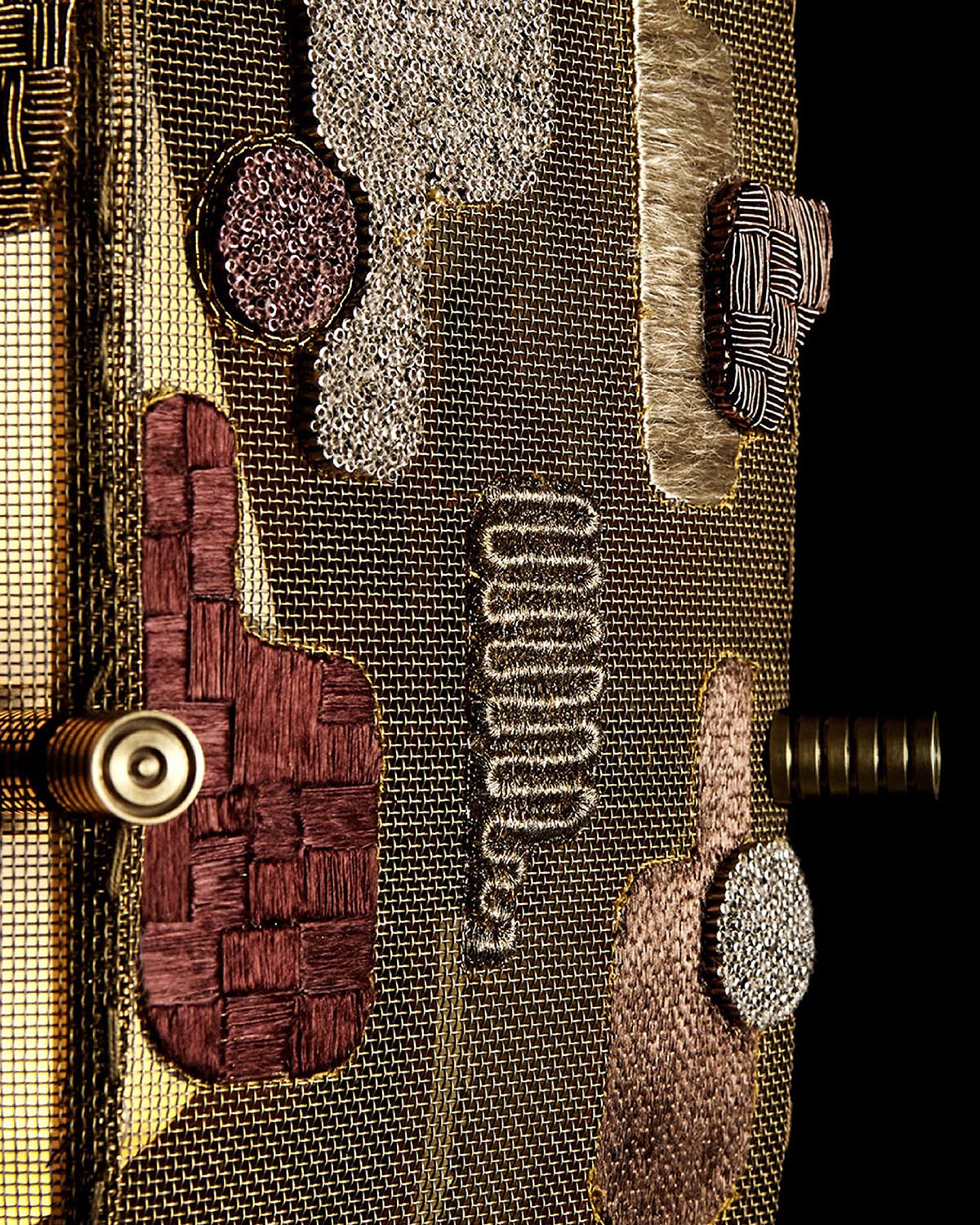 Close-up of hand-embroidered fabric panel with textured stitches and metallic mesh background on a floor lamp detail