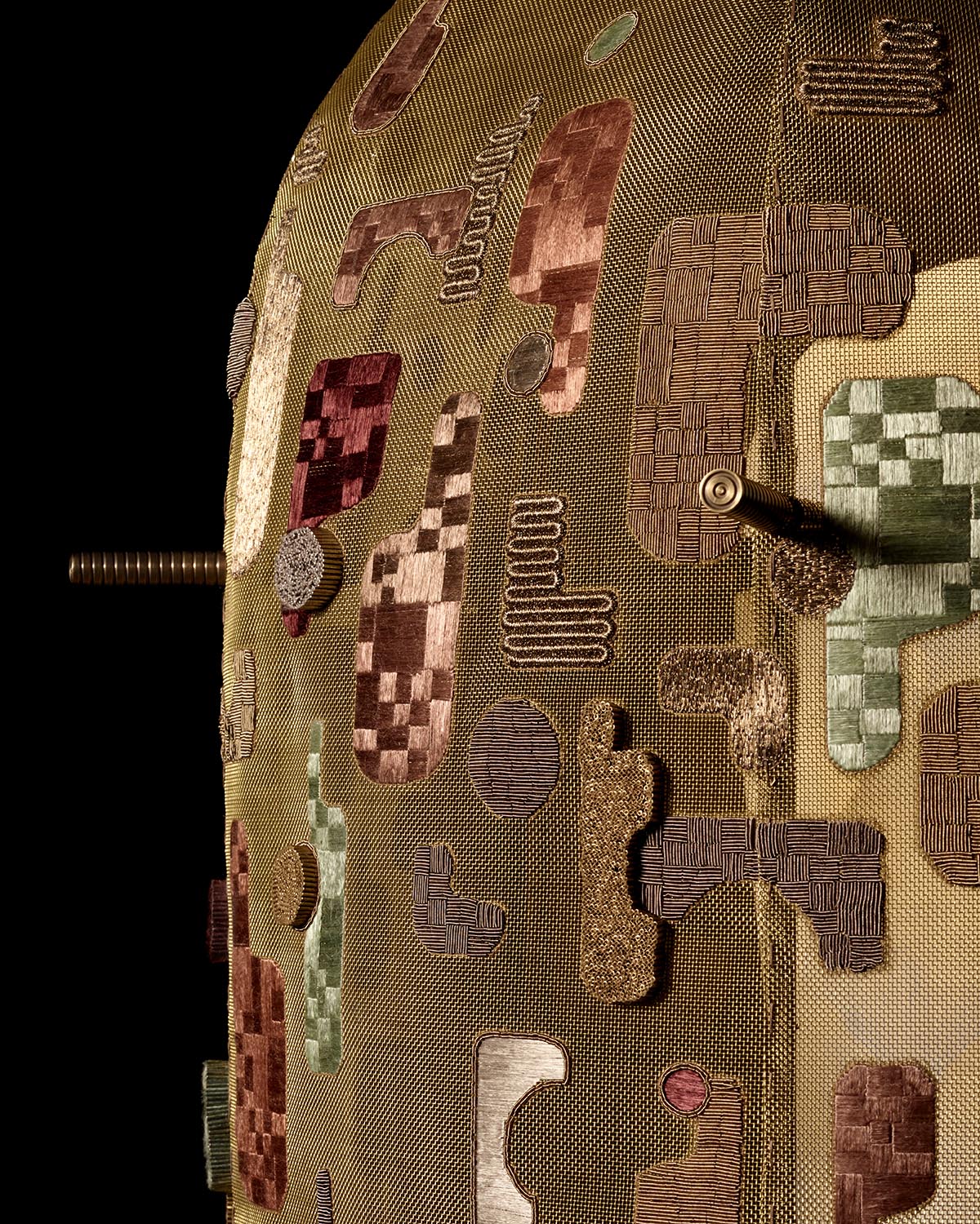 Close-up of hand-embroidered hanging lamp with abstract geometric patterns in earthy tones on textured fabric