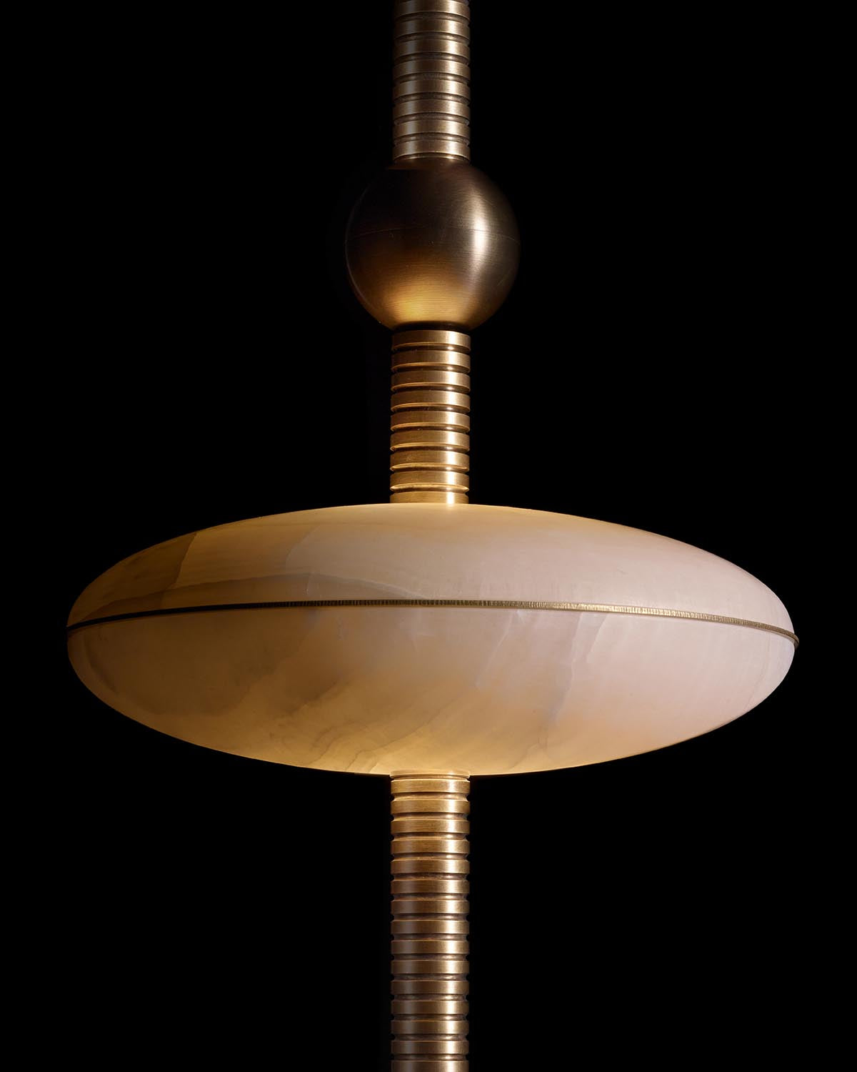 Close-up of a hand-embroidered hanging lamp with a smooth round shade and ribbed metallic rod on black background