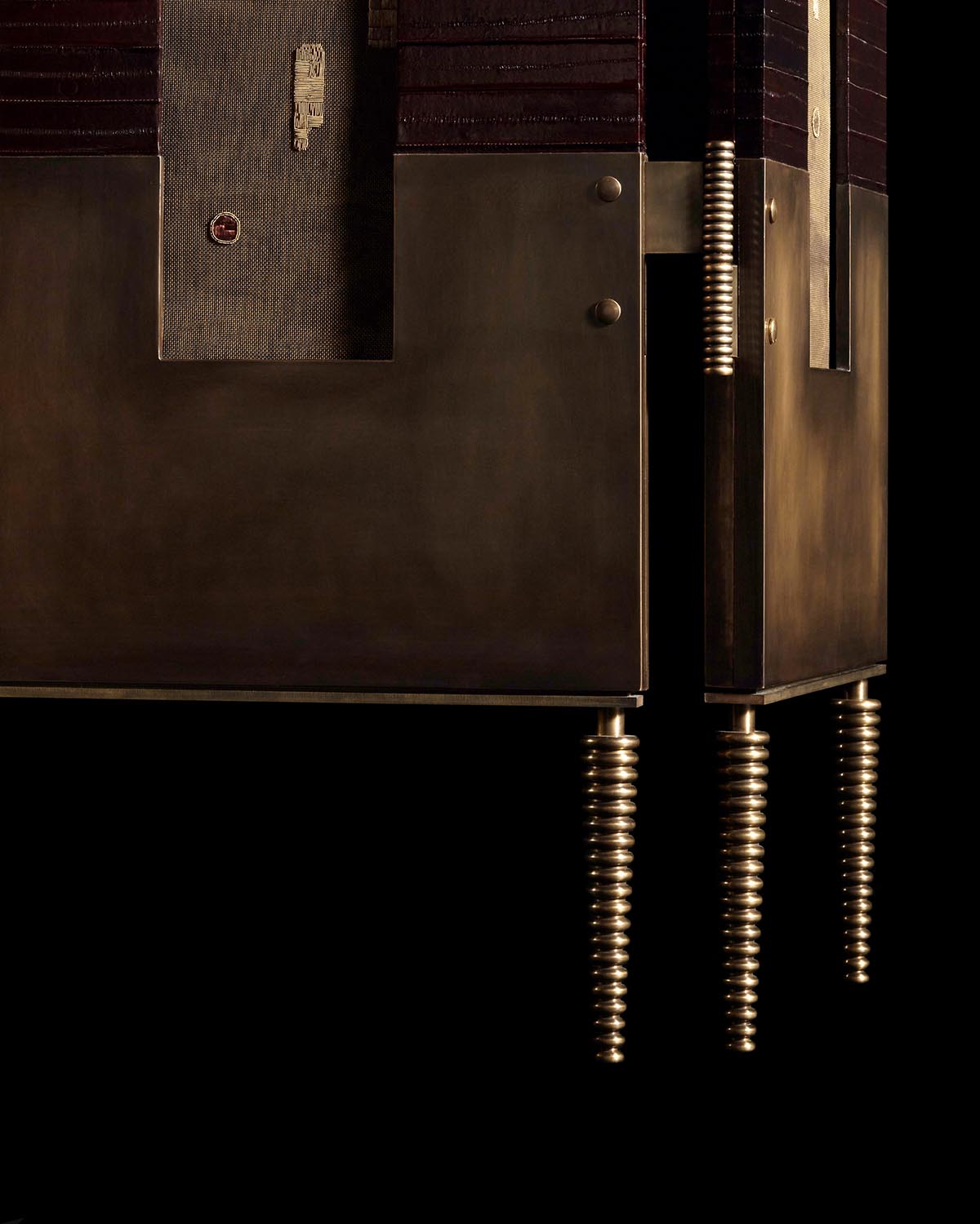 Close-up of a dark bronze screen corner with textured fabric panel and spiral cylindrical legs against a black background