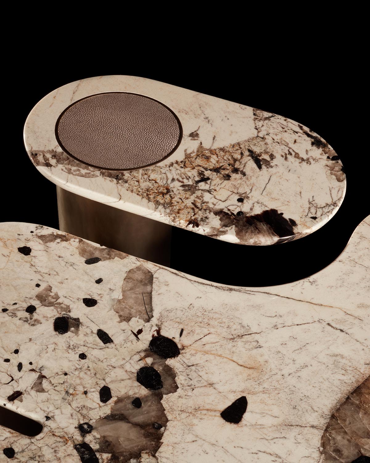Close-up of an oval marble table top with intricate natural patterns and a built-in round leather insert on a dark base