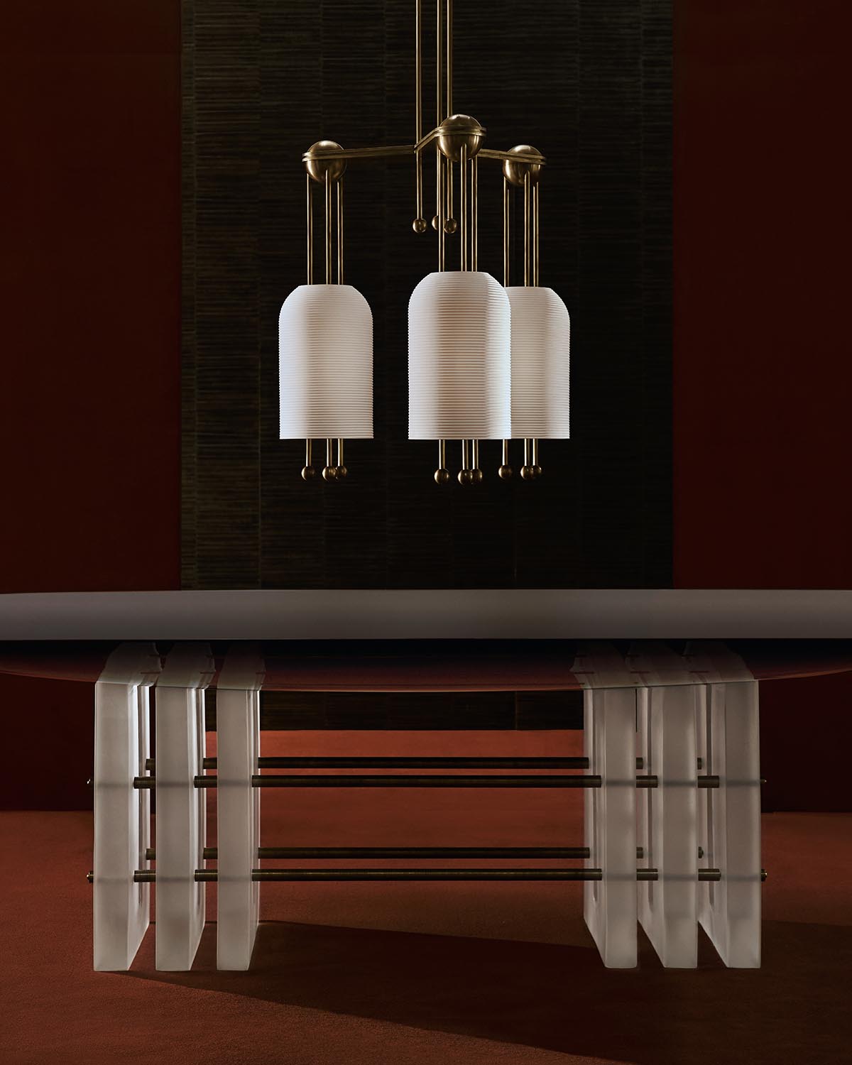 Three modern white pendant lights with brass accents hanging above a clear acrylic table base on a brown floor