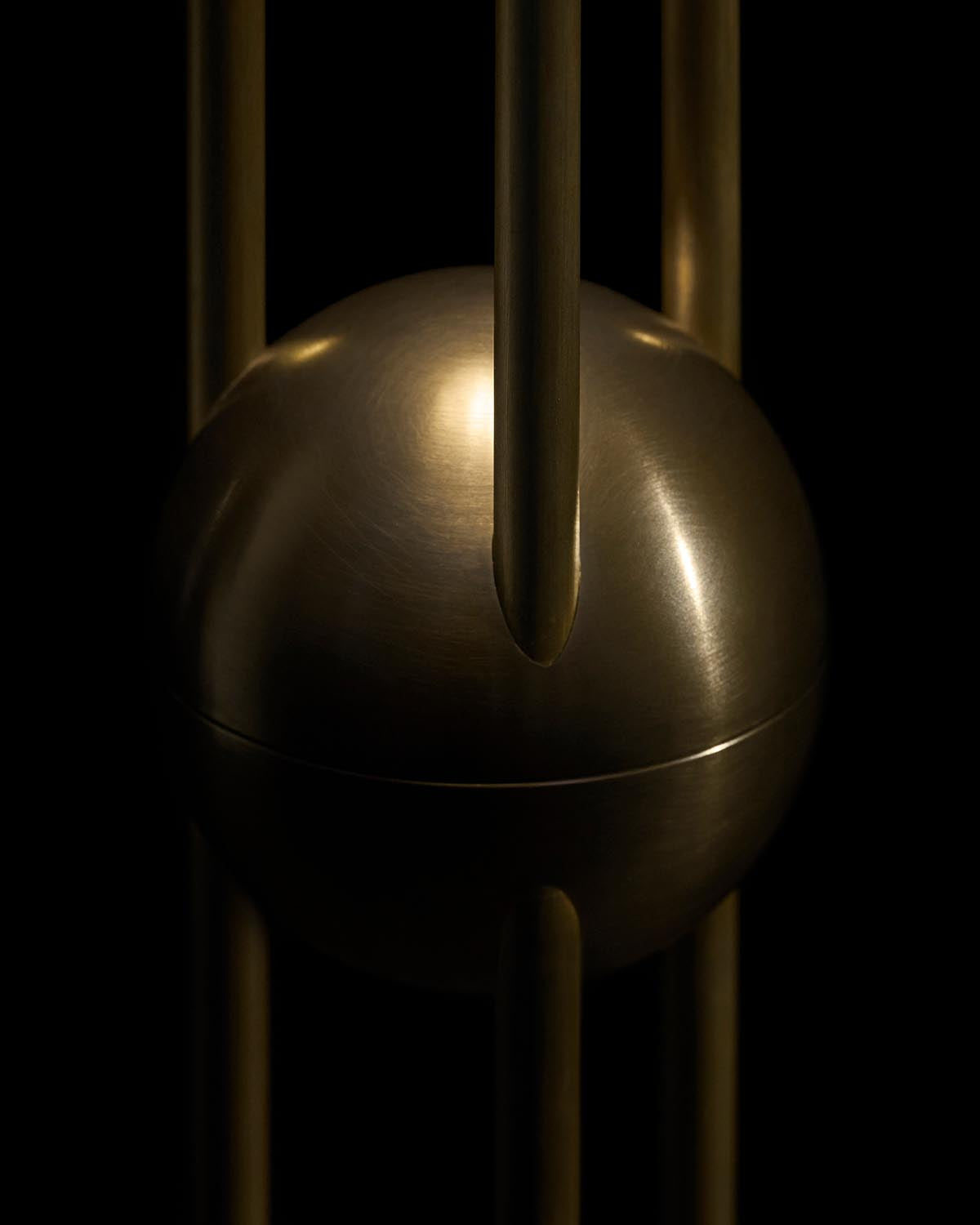 Close-up of a brushed metallic sphere suspended within vertical cylindrical rods against a black background